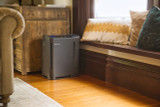 Brondell Revive air purifier and humidifier in black placed in the cozy corner of a living room
